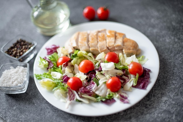 plato con filete de pollo y ensalada con verduras sobre un fondo de piedra