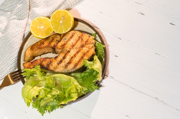 Plato de filete de salmón a la plancha con ensalada en mesa de madera. Vista superior