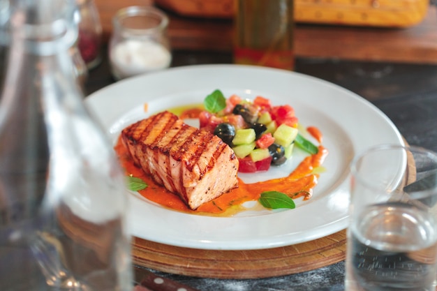 Plato de filete de salmón a la plancha con verduras en mesa de madera