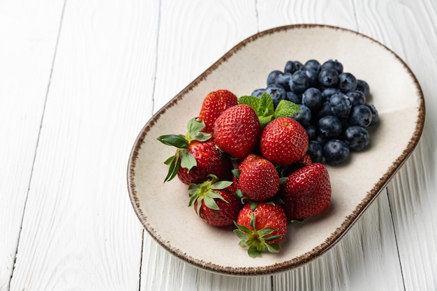 Foto un plato de fresas y arándanos sobre una mesa blanca