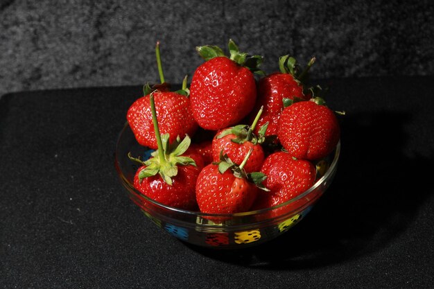 Un plato de fresas con hojas verdes.