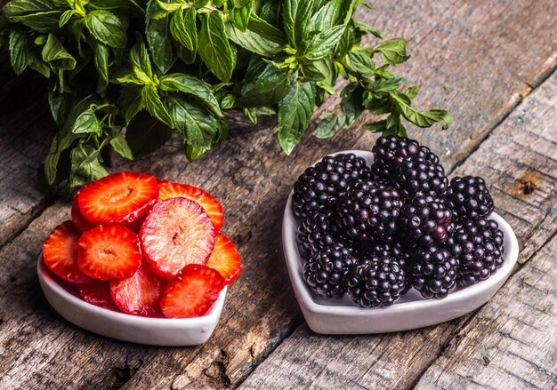 Un plato de fresas y moras sobre un fondo de madera