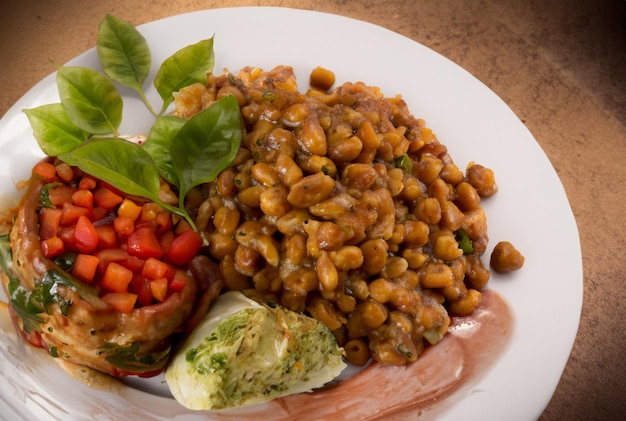 Un plato de frijoles y una salchicha con un lado de verduras.