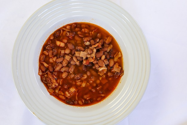 Foto plato de frijoles servido en mesa con mantel blanco comida tradicional mexicana