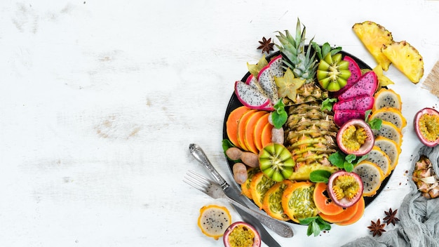 Un plato de frutas tropicales en rodajas Vista superior Espacio libre para texto