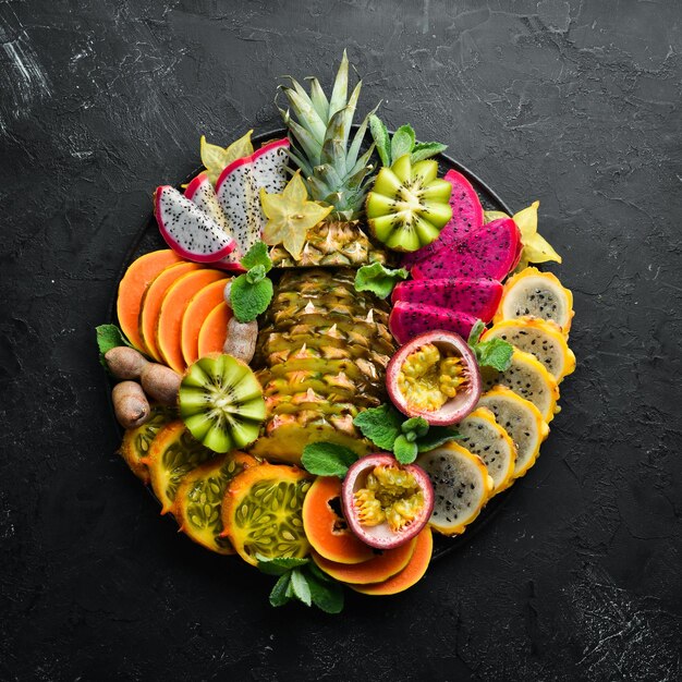 Un plato de frutas tropicales en rodajas Vista superior Espacio libre para texto