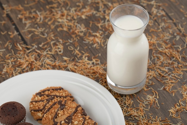 Plato de galletas de avena con cupcakes y una jarra de leche