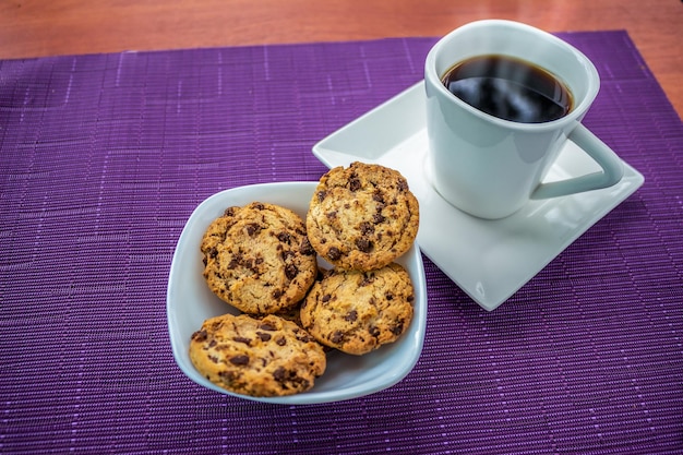 Plato de galletas con trocitos de chocolate y taza de café