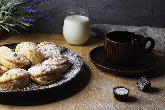 Un plato de galletas con un vaso de leche y una taza de té sobre la mesa.