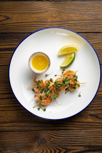 Un plato de gambas al ajillo con un tazón pequeño de rodajas de limón.