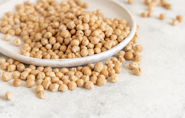 Plato de garbanzos secos crudos en el cuadro blanco de cerca