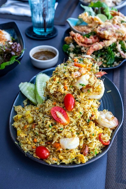 Un plato grande de arroz frito con piña de marisco se ve delicioso en un plato de porcelana En una mesa en un restaurante Hay otros platos en el fondo Enfoque selectivo