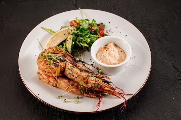 Plato de grandes camarones con hierbas sobre fondo de madera