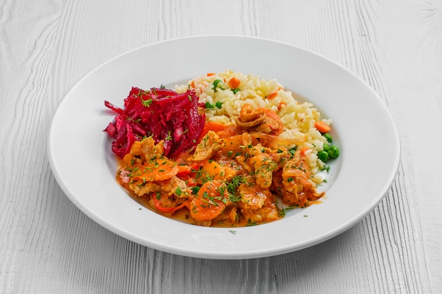 Plato con gulash de ternera, arroz con guisantes y ensalada de remolacha