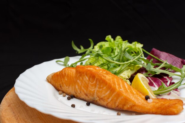 En un plato hay un filete de salmón jugoso con ensalada.