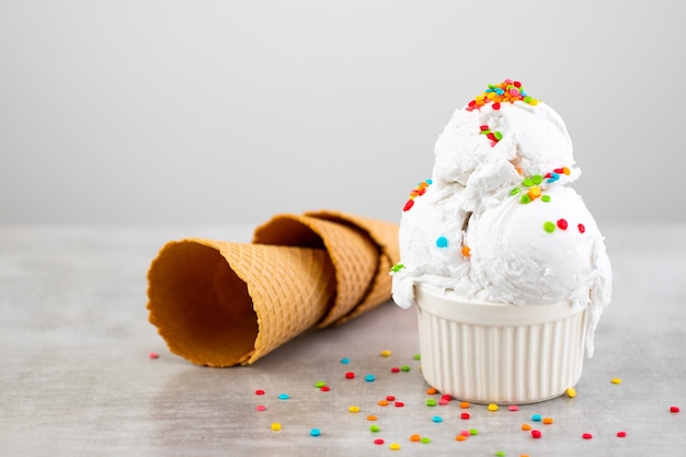 Plato de helado de vainilla con bolas de helado y conos de gofre