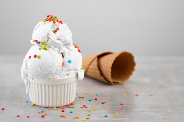 Plato de helado de vainilla scoop swith sprinkles y conos de waffle con espacio de copia.