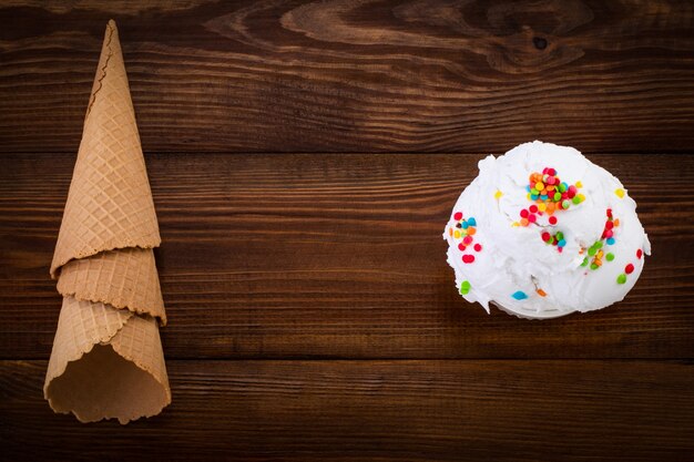 Plato de helado de vainilla scoop swith sprinkles y conos de waffle sobre fondo de madera con espacio de copia.