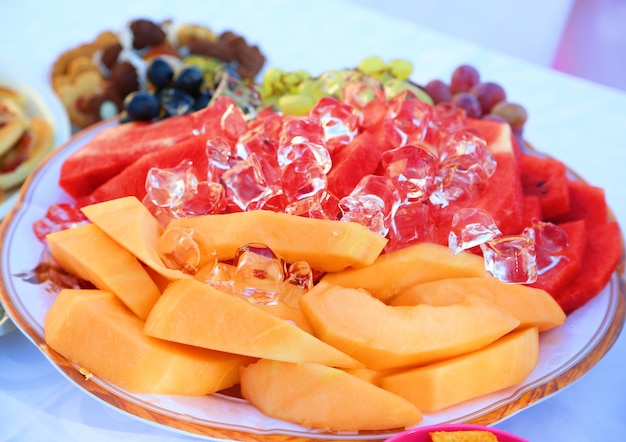 Plato de hielo de frutas con mesa de fiesta.