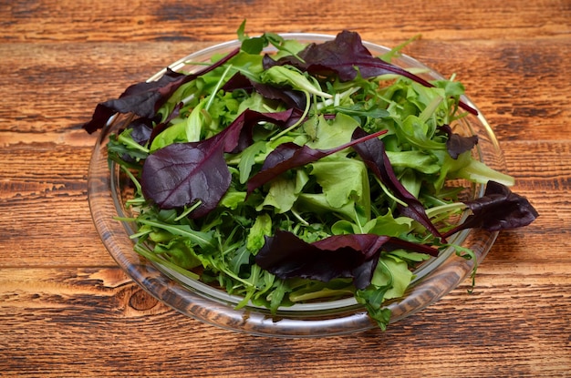 Plato con hojas de lechuga fresca sobre fondo de madera