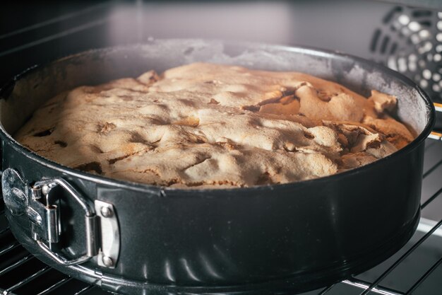 Plato para hornear con pie de manzana en horno negro. Panadería casera de temporada