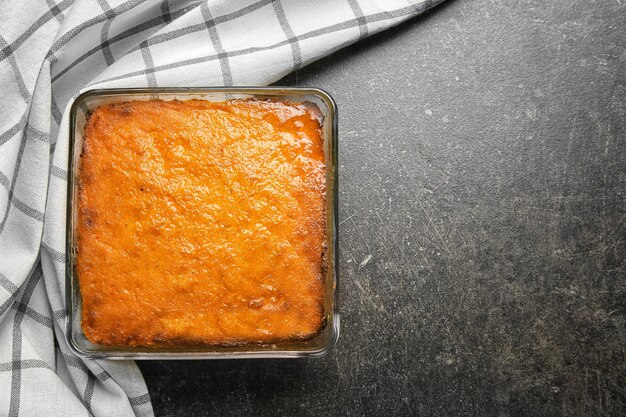 Plato para hornear con sabroso soufflé de zanahoria sobre fondo gris