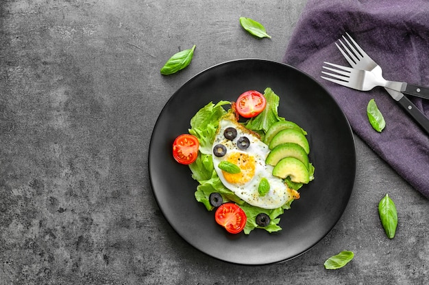 Plato con huevo frito y verduras sobre mesa oscura