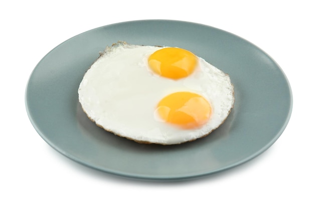 Plato con huevos fritos al lado soleado sobre fondo blanco.