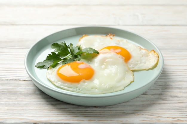 Plato con huevos fritos en la mesa de madera, de cerca