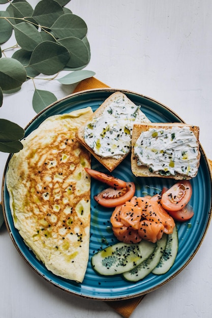 Plato con huevos revueltos salmón pepino y tostadas de queso crema servido para el desayuno