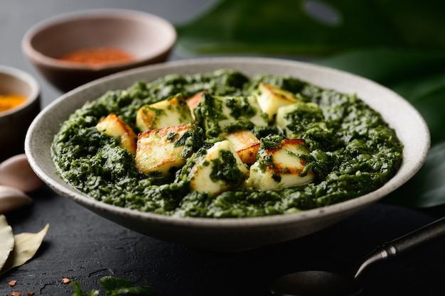 Plato indio Palak Paneer sobre fondo negro, enfoque selectivo