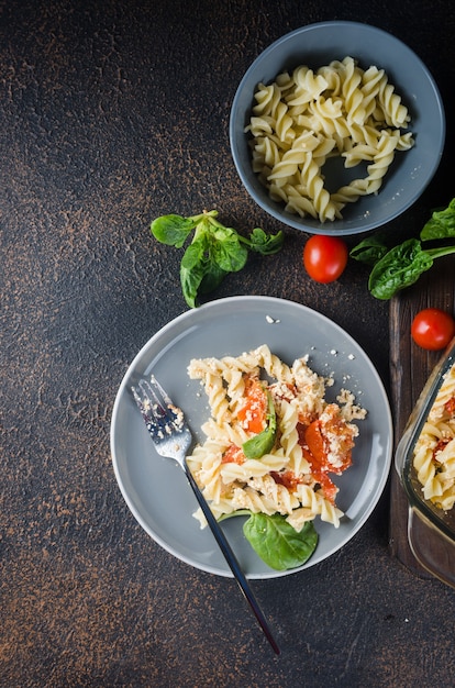Plato italiano de pasta mezclada con queso feta al horno y tomates sobre un fondo oscuro. Fetapasta.