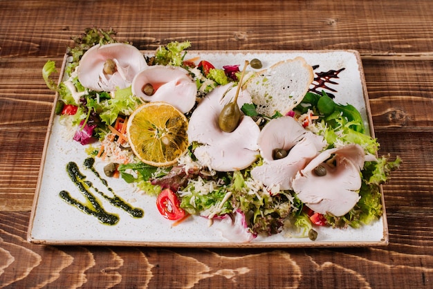 Un plato con jamón ahumado y verduras sobre fondo de madera