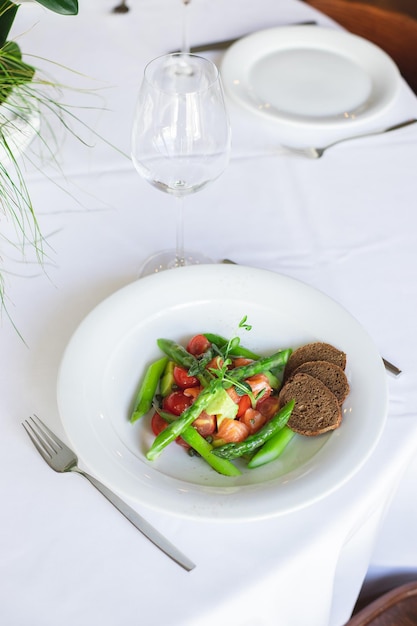 Un plato de judías verdes y tomates con pan sobre la mesa