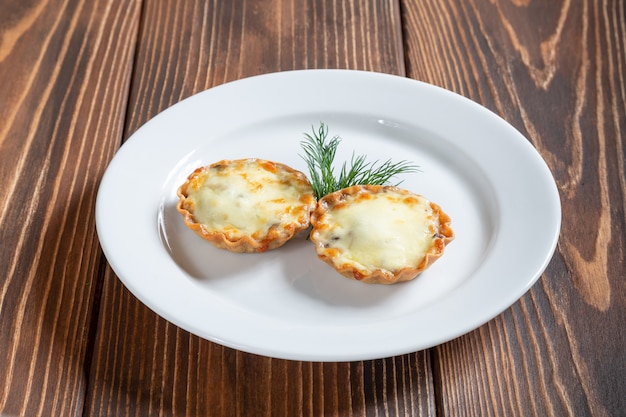 Plato de juliana con queso y champiñones sobre una mesa de madera