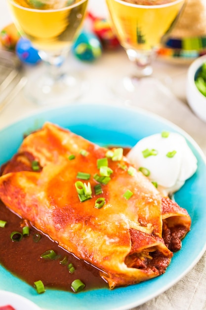 Plato llano con enchiladas de pollo aderezado con cebollas verdes y crema agria.