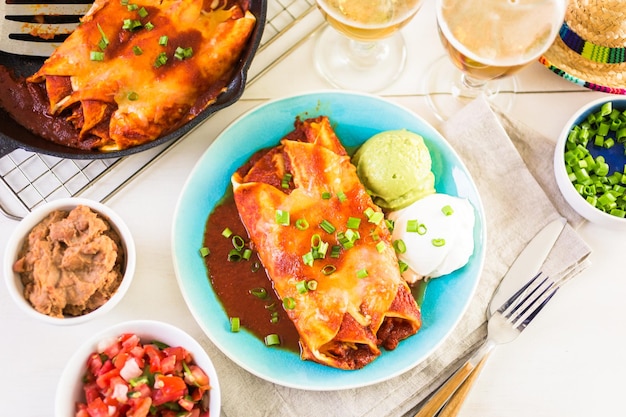 Plato llano con enchiladas de pollo aderezado con cebollas verdes y crema agria.