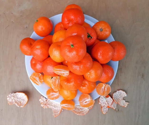 Un plato lleno de clementinas sobre un fondo de madera