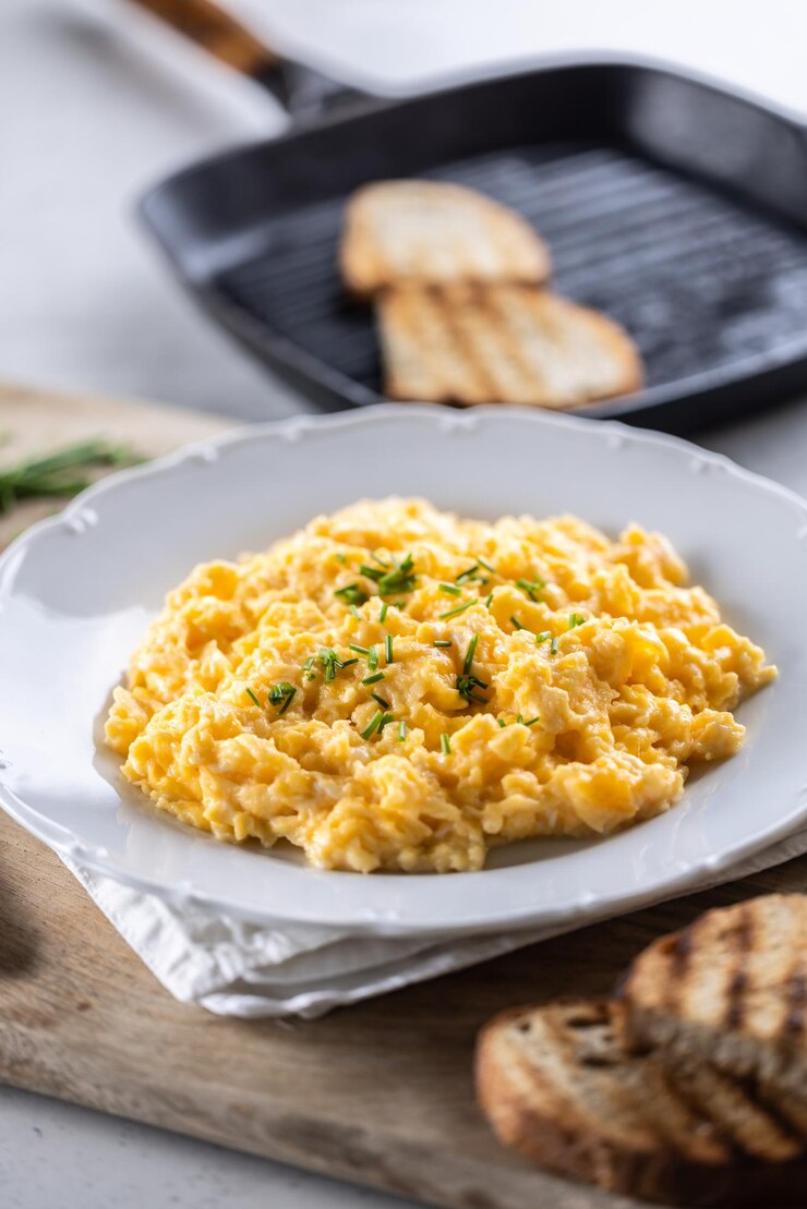 Plato lleno de huevos revueltos frescos para el desayuno con pan tostado a la parrilla