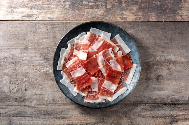 Foto plato de lonchas de jamón serrano español sobre mesa de madera