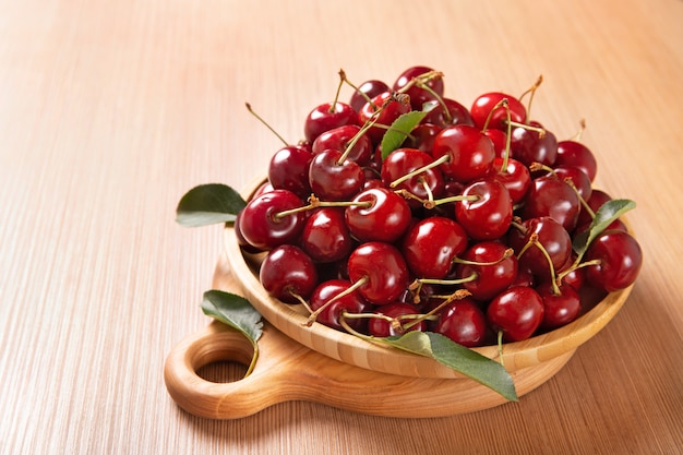 Plato de madera con cerezas sobre la mesa