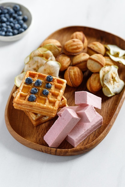 Plato de madera con dulces gofres y pastillas Dulces naturales Chips de manzana