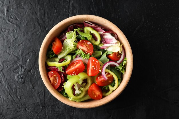 Plato de madera con ensalada en negro