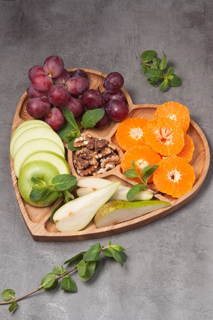 Plato de madera en forma de corazón con fruta y nuez