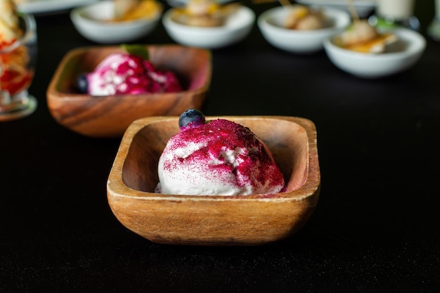 Plato de madera de helado de arándano En el fondo hay platos de catering Vista frontal