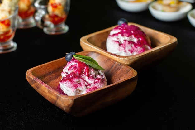 Plato de madera de helado de arándanos con cobertura de color de bayas frescas En el fondo hay catering