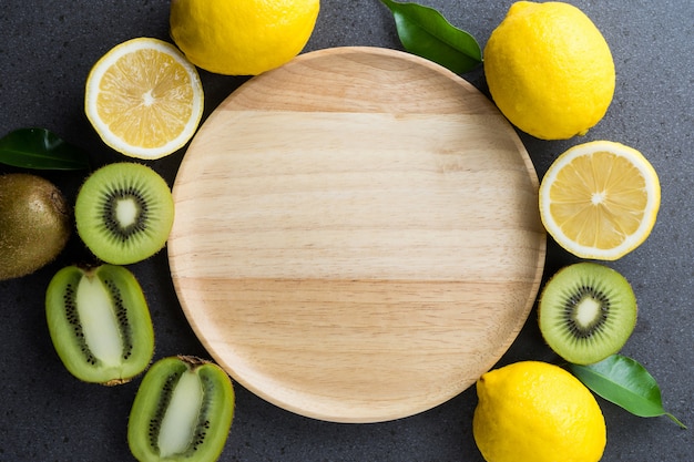 Plato de madera con kiwi y limón en plano.