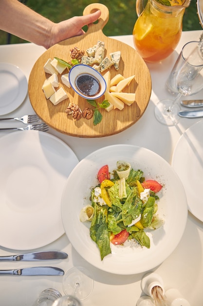 Plato de madera con mezcla de queso y plato blanco con ensalada verde del chef experto