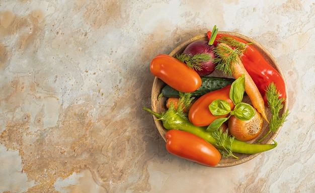 Plato de madera con verduras frescas pimiento verde tomate cebolla zanahoria pepino albahaca eneldo sobre fondo marrón vista superior concepto rústico