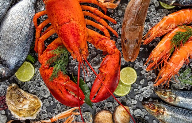 Foto plato de mariscos con langosta, camarones, pescado, mariscos y hierba de limón. buffet de mariscos, mariscos frescos crudos en la vista superior del hielo.